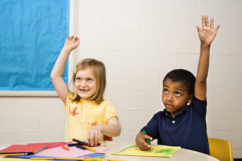 Boy and Girl raising hands in art class. Horizontally framed shot.